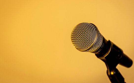 A microphone on a stand against a yellow background.