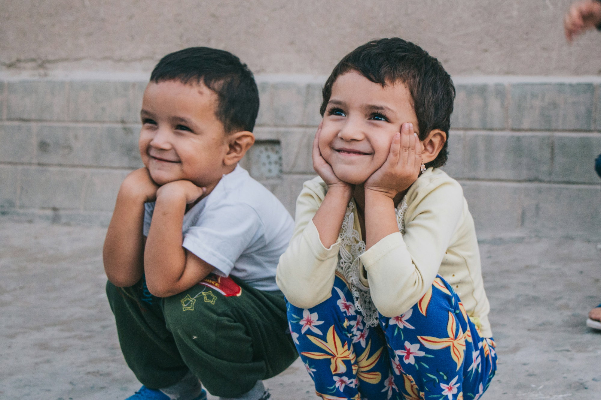 two-young-boys-sitting-on-the-ground-smiling.jpg two young boys sitting on the ground smiling
